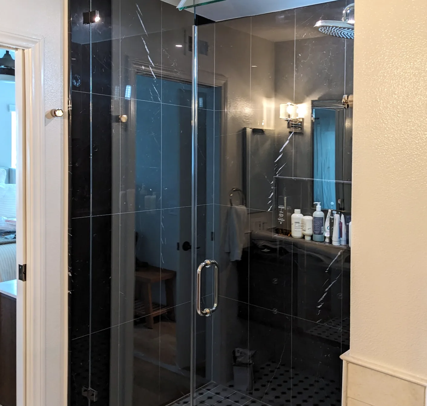 Frameless glass shower door we installed in a black marble shower