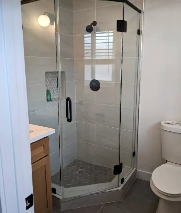 Neo-angle frameless glass shower enclosure with matte black hardware