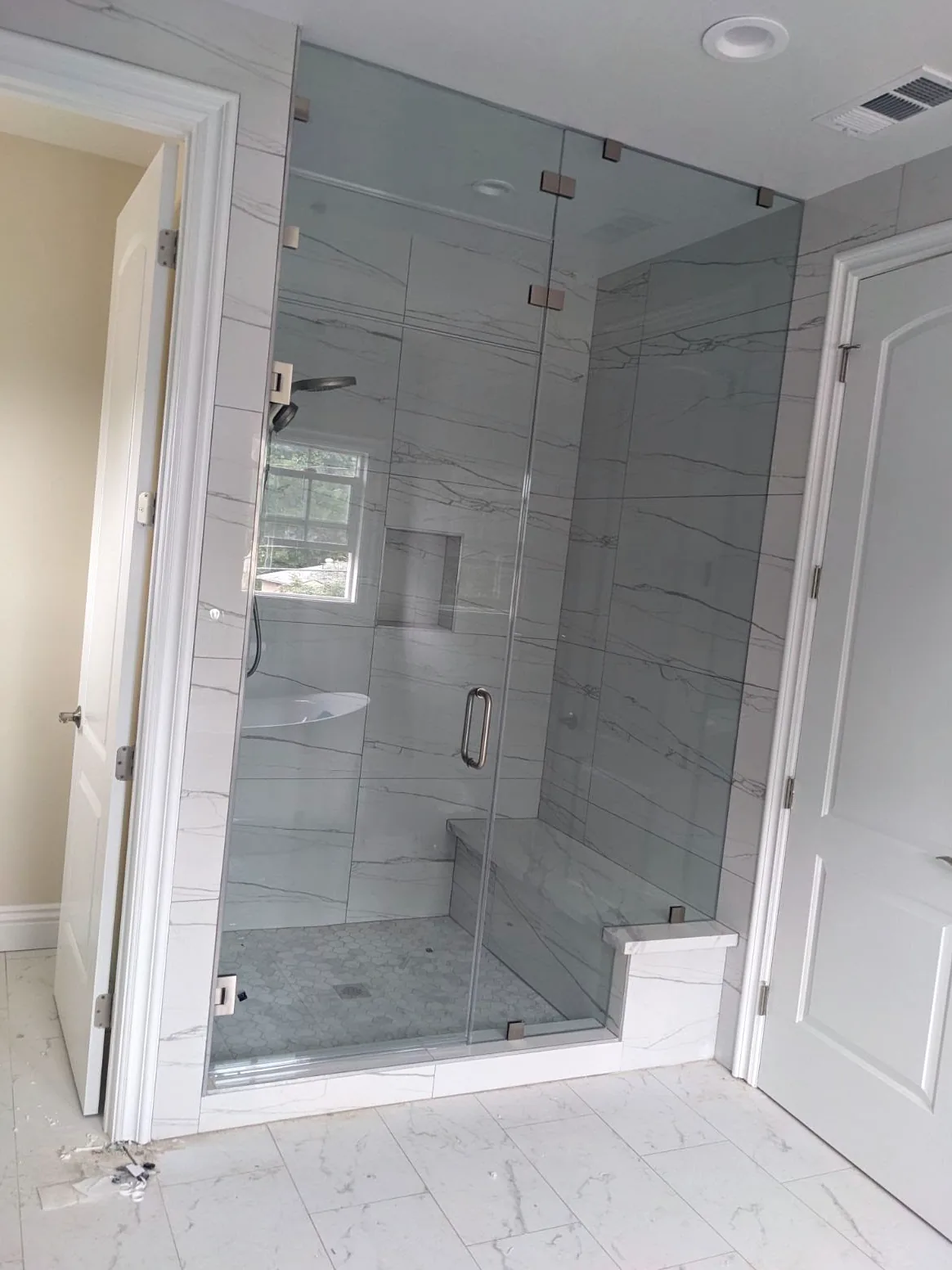 Frameless glass corner shower enclosure with a built-in bench