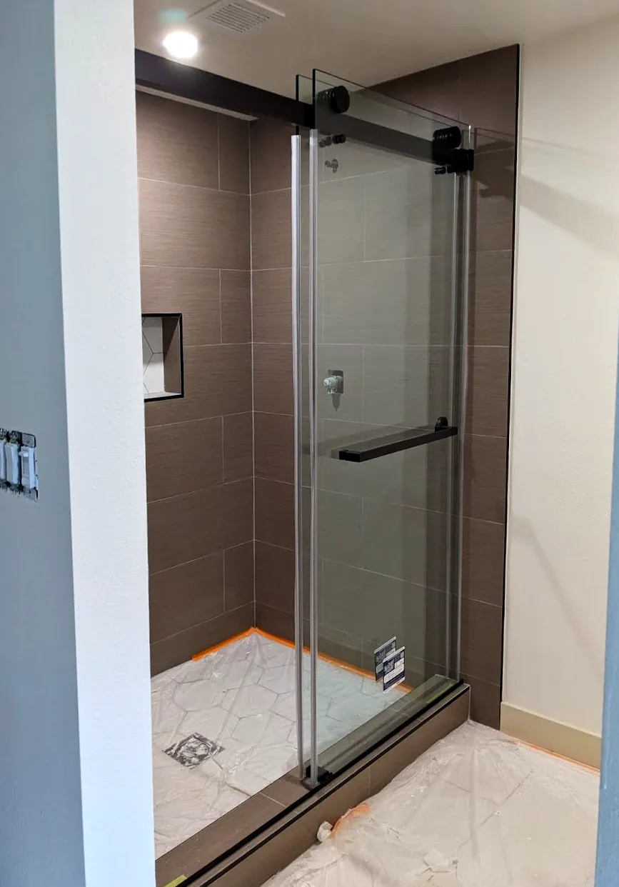 Sliding glass shower door with matte black roller hardware